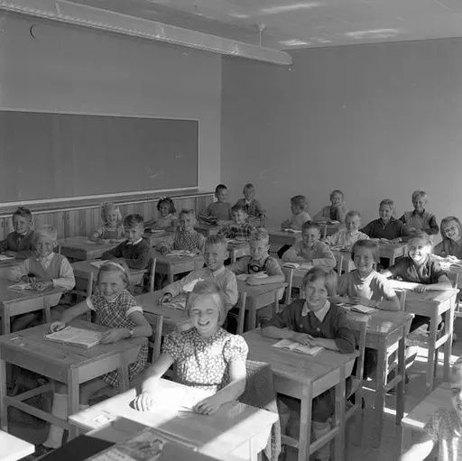 Svartvit bild av elever vid skolbänkar i ett klassrum